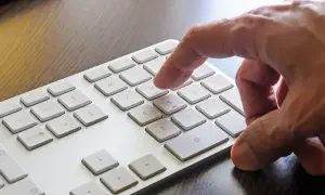 Dłoń naciska klawisz 8 na klawiaturze numerycznej, aktywując funkcję num lock.