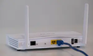 Biały modem a router z dwoma antenkami, podłączony niebieskim kablem Ethernet.