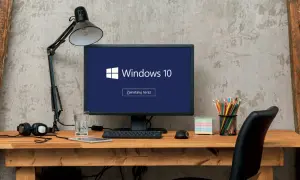 Biurko z komputerem Windows 10, lampką, słuchawkami i szkłem wody. Zastanawiasz się, jak wyłączyć komputer?