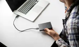 Mężczyzna podłącza dysk zewnętrzny do laptopa, przygotowując się do użycia narzędzia diskpart.