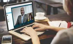 Kobieta prowadzi rozmowę przez Skype z dwoma współpracownikami.