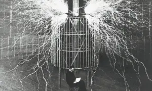 Nikola Tesla, który udowodnił, kto wynalazł prąd, siedzi bezpiecznie w klatce podczas eksperymentu z wyładowaniami elektrycznymi.
