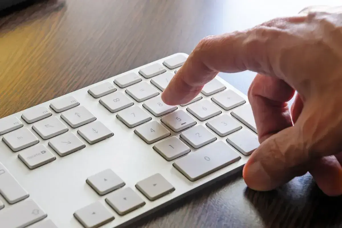 Dłoń naciska klawisz 8 na klawiaturze numerycznej, aktywując funkcję num lock.