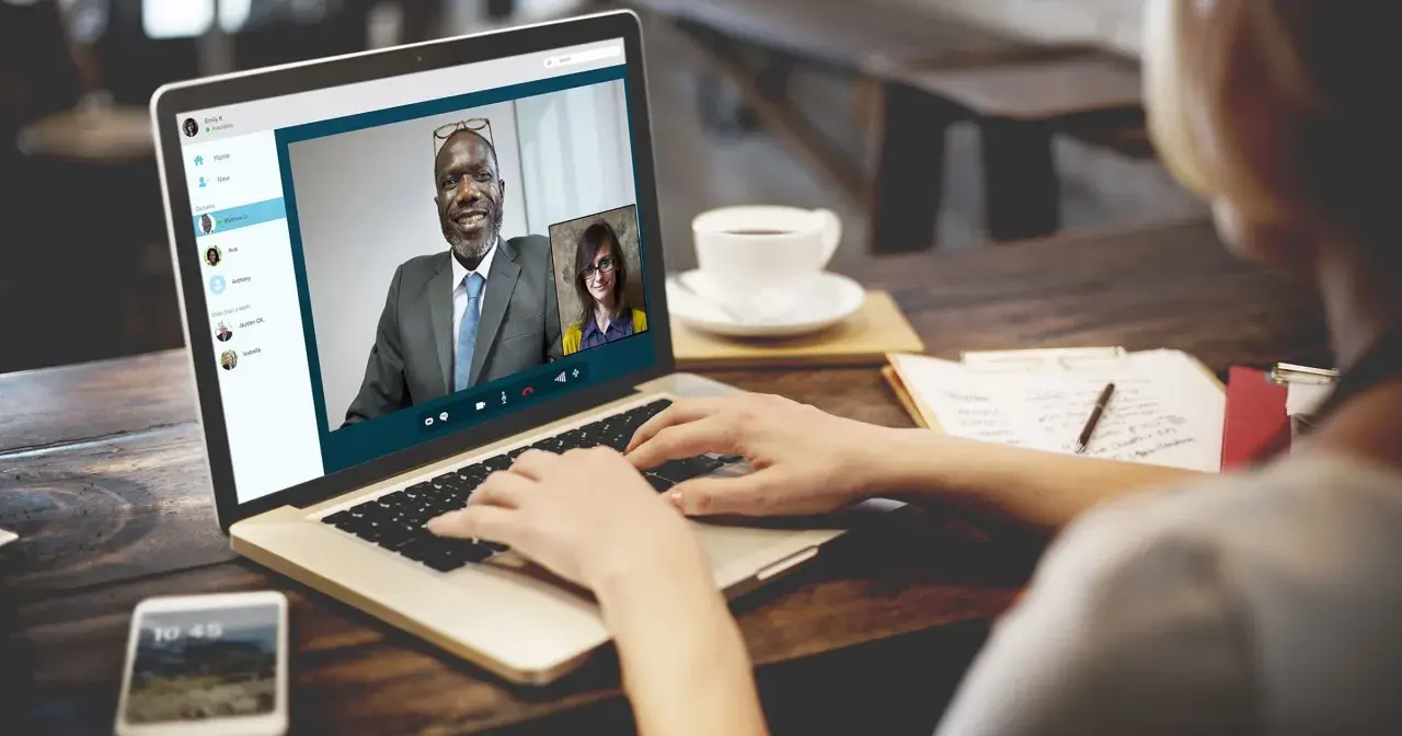 Kobieta prowadzi rozmowę przez Skype z dwoma współpracownikami.